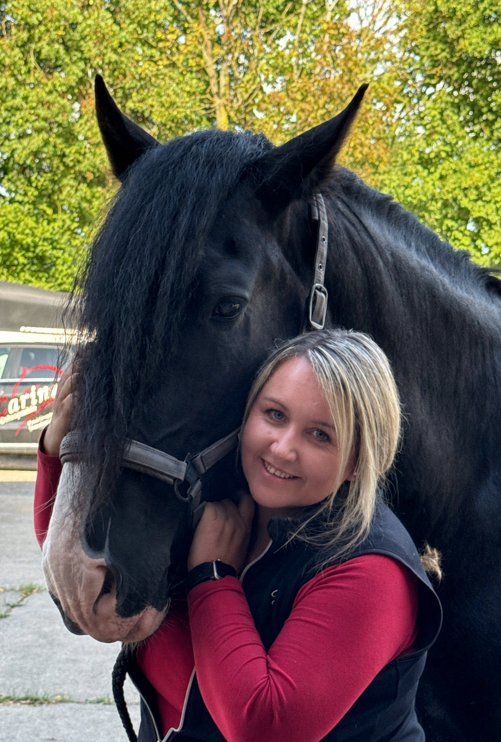 Carina Wick lächelt neben einem schwarzen Pferd
